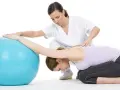 Therapeutin unterstützt Frau bei Bobath-Therapie für Erwachsene mit Gymnastikball.