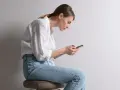 Frau mit gebeugtem Rücken und Handy. Schlechte Haltung kann zu einem Buckel im Nacken Ursache sein.