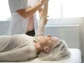 Physiotherapeutin unterstützt ältere Frau bei der Armbewegung. Dies ist Teil einer mld behandlung zur Verbesserung der Beweglichkeit.