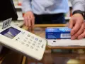 Krankenkassenkarte steckt in Terminal, Hand greift nach Medikamentenpackung.