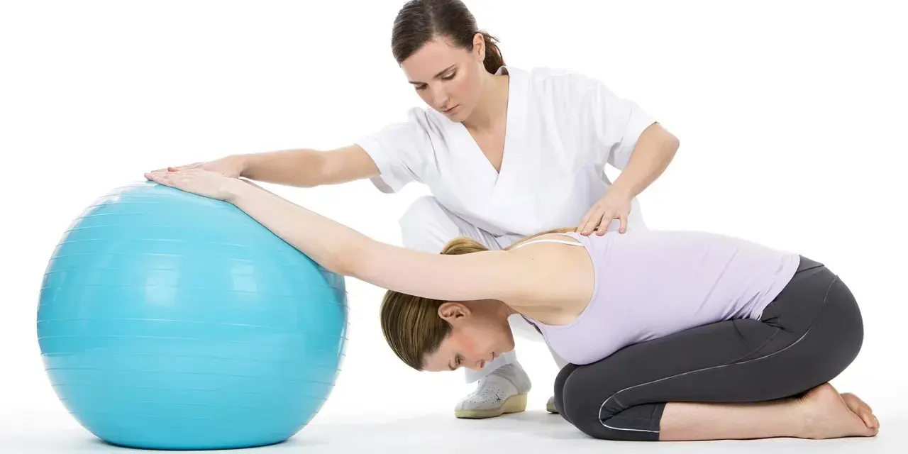 Therapeutin unterstützt Frau bei Bobath-Therapie für Erwachsene mit Gymnastikball.