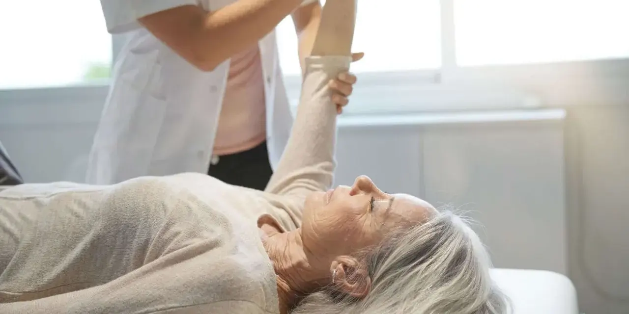 Physiotherapeutin unterstützt ältere Frau bei der Armbewegung. Dies ist Teil einer mld behandlung zur Verbesserung der Beweglichkeit.