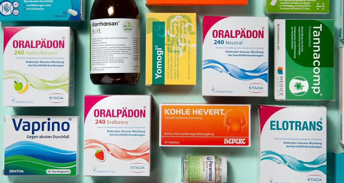 Medikamentenpackungen und eine Flasche Saft gegen Durchfall, auf blauem Hintergrund.