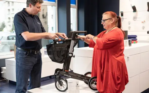 Mann erklärt einer Frau einen Rollator, ein wichtiges medizinisches Hilfsmittel, im Sanitätshaus.