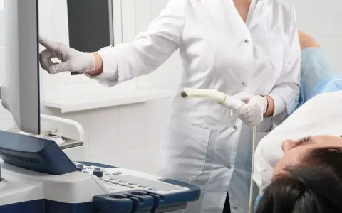 Arzt mit Ultraschallsonde und Patientin bei gynäkologischer Untersuchung.