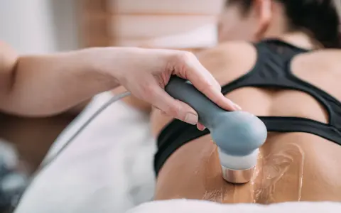 Therapeutin führt Ultraschall Physiotherapie am Rücken einer Patientin durch. Gel auf der Haut für die Behandlung.