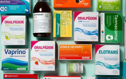 Medikamentenpackungen und eine Flasche Saft gegen Durchfall, auf blauem Hintergrund.
