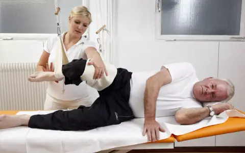 Physiotherapeutin hilft Mann bei Übungen. Die Krankenkasse bezahlt solche Behandlungen zur Genesung.