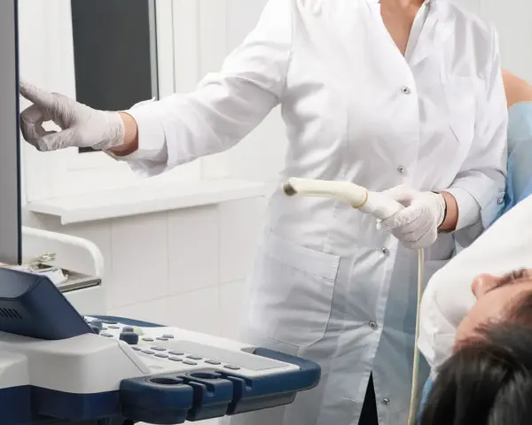 Arzt mit Ultraschallsonde und Patientin bei gynäkologischer Untersuchung.
