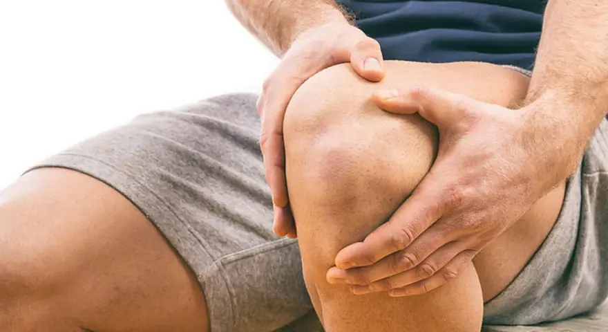 Mann hält schmerzendes Knie. Schmerzen beim Knien auf hartem Boden sind deutlich zu sehen.