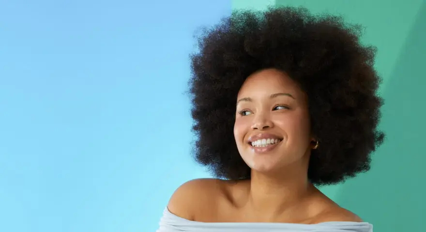 Lächelnde Frau mit Afro-Frisur vor blau-grünem Hintergrund.