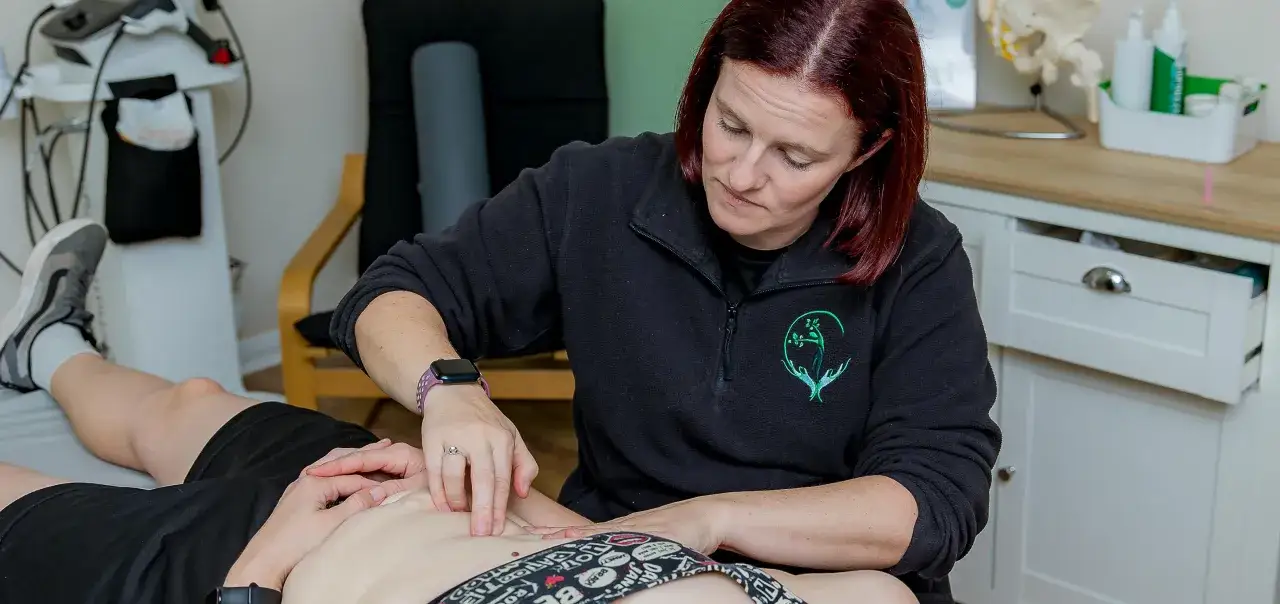 Therapeutin führt eine mld behandlung am Bauch eines Patienten durch.
