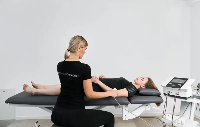 Physiotherapeutin führt Ultraschalltherapie an einem Arm durch. Die Krankenkasse übernimmt die Kosten für diese Behandlung.